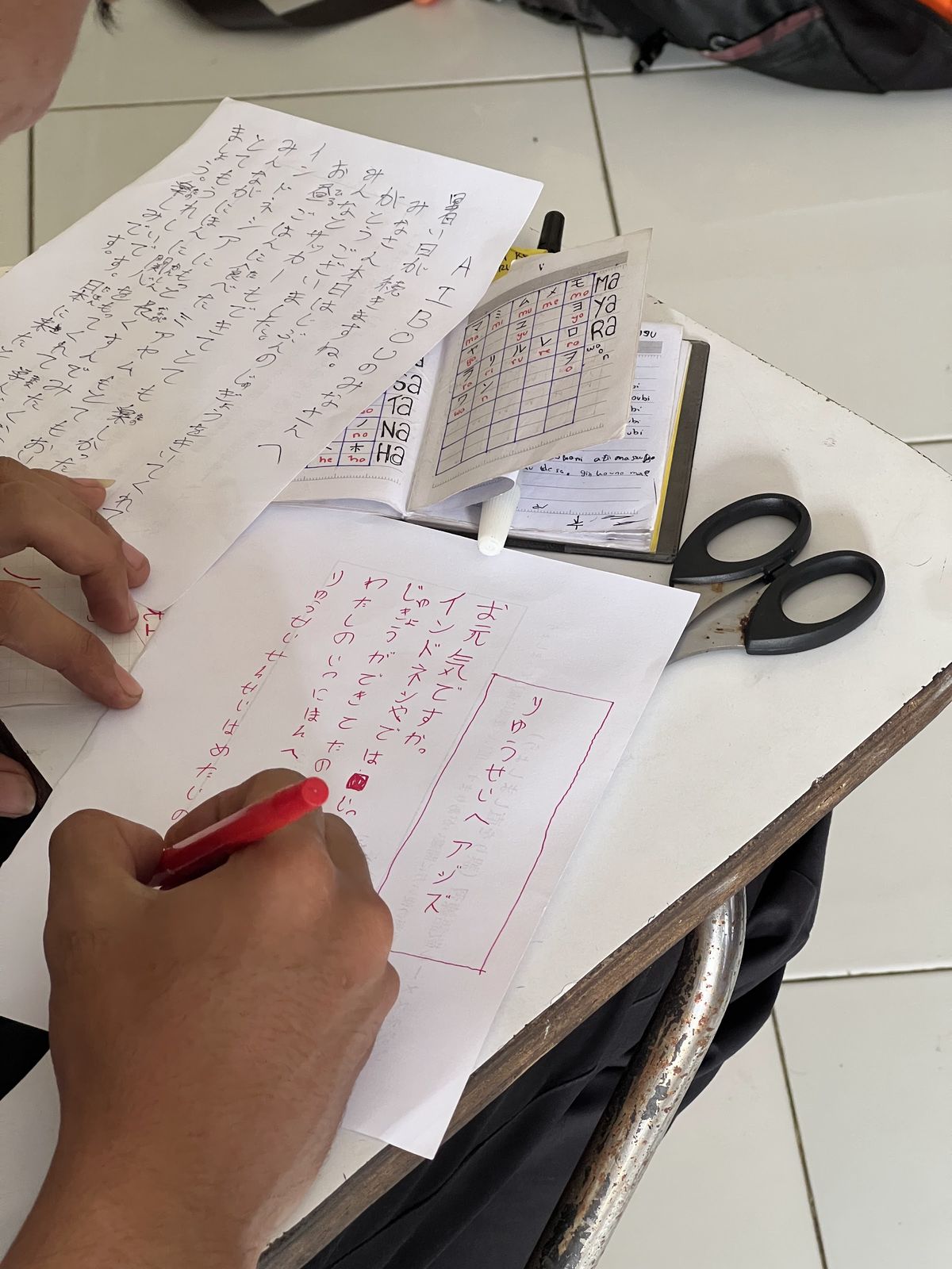 赤ペンで日本語の手紙を書く受講生の手元