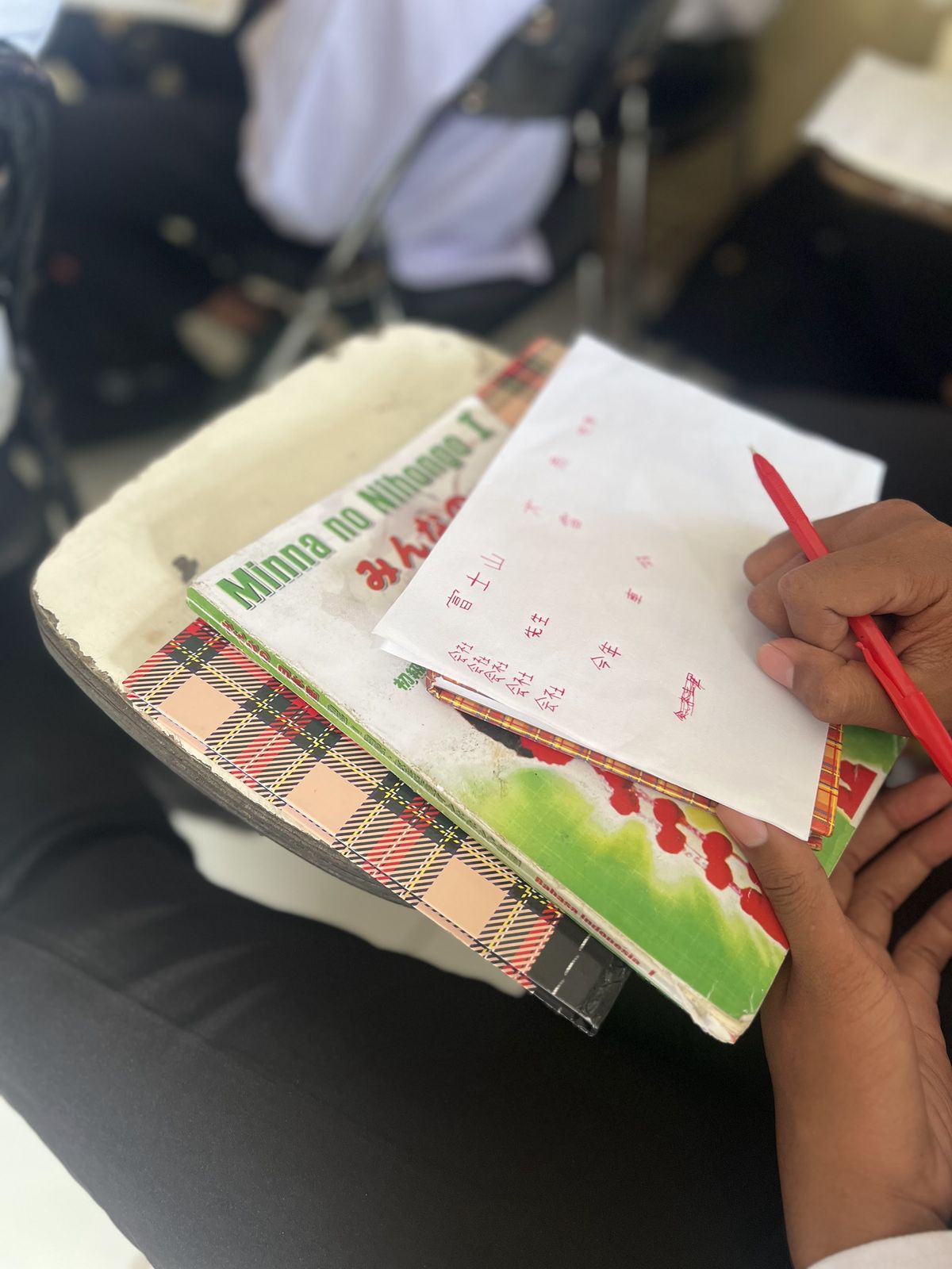 赤ペンを持ってワークブックに書き込む手