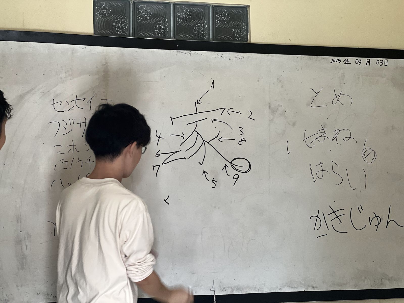 ホワイトボードに書き順を書く受講生